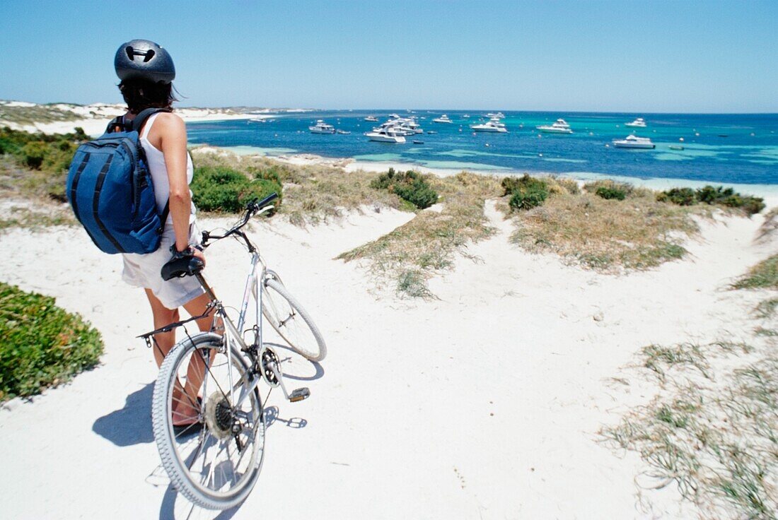 Female Tourist Standing With Bicycle On The Beach