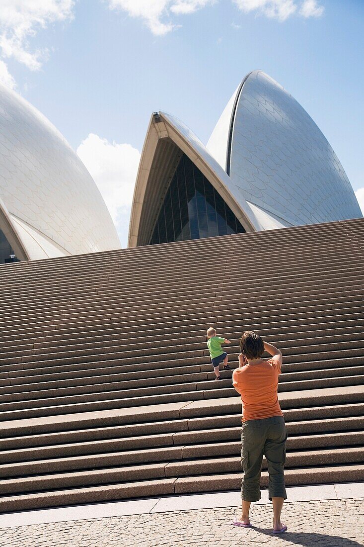 Mother Photographing Her Son Ascending Stairs In Front Of Sydney Opera House