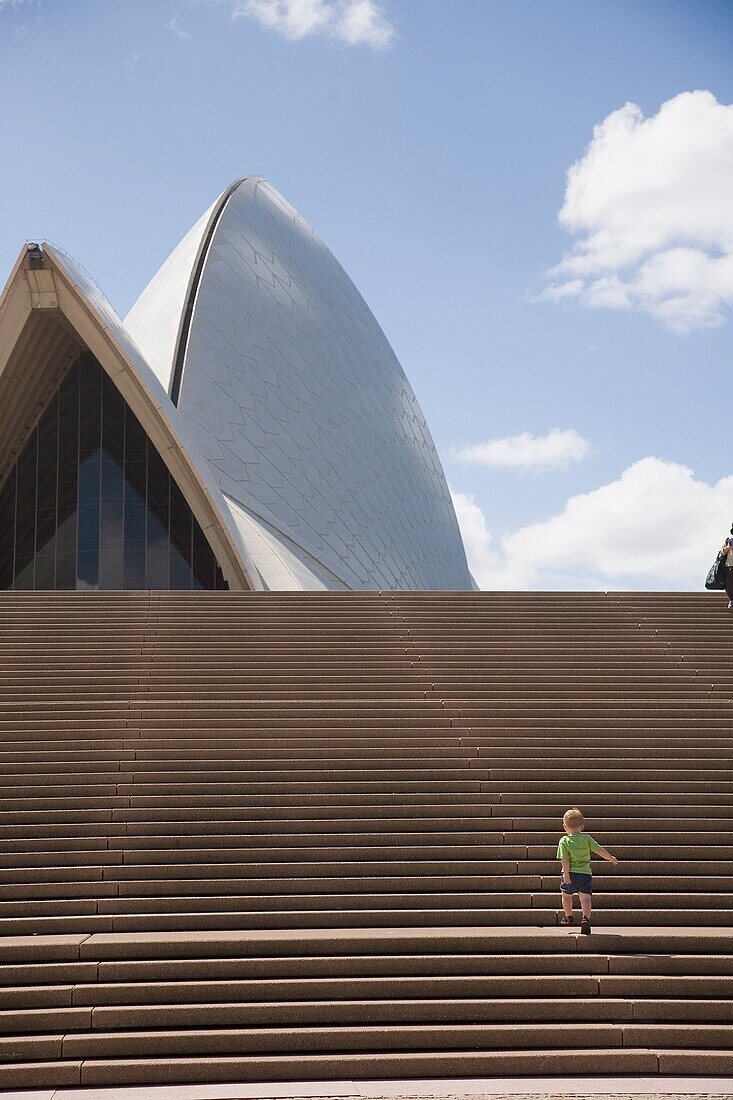 Junger Junge steigt die Treppe vor dem Opernhaus von Sydney hinauf