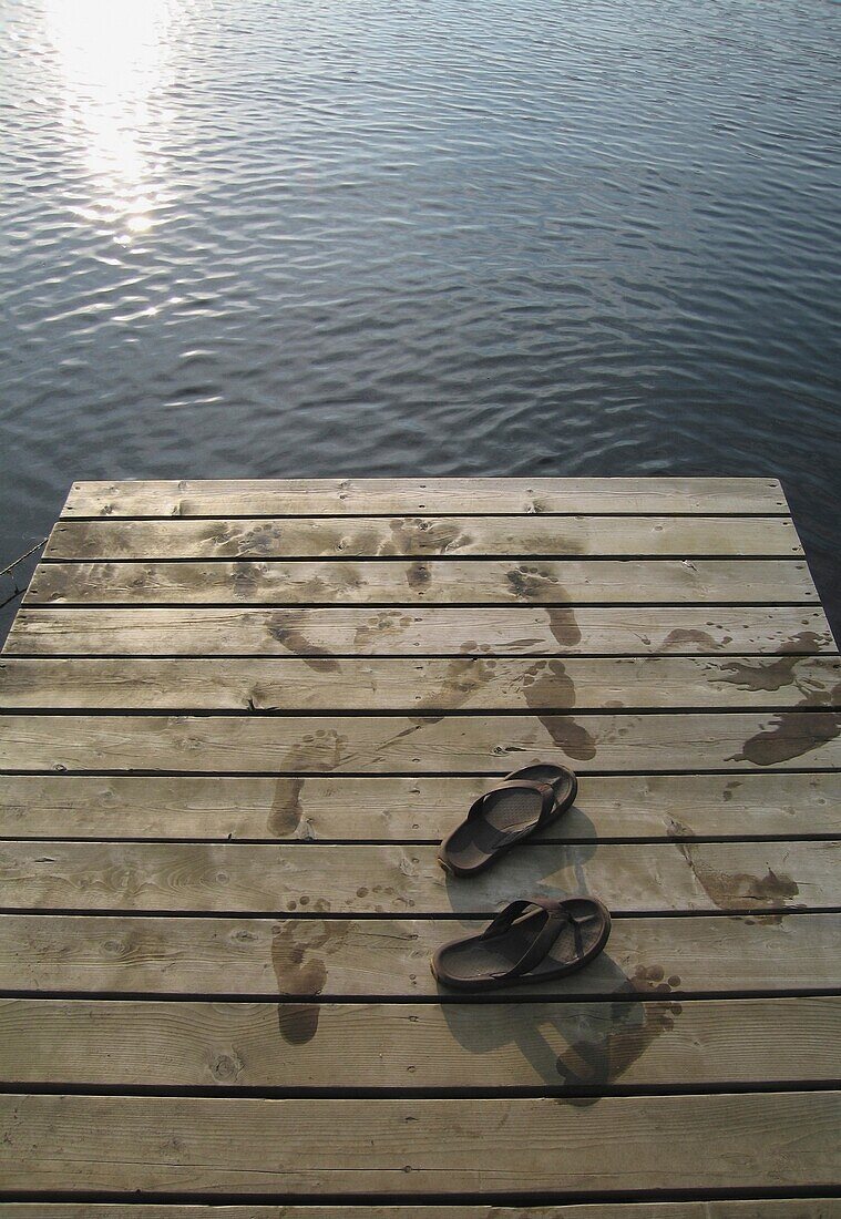 Sandalen auf einem hölzernen Steg am See