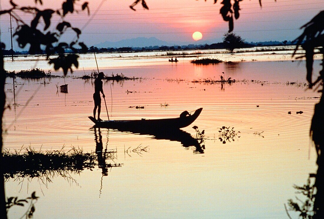 Silhouetted Person On A Boat On The Mekong River At Sunset