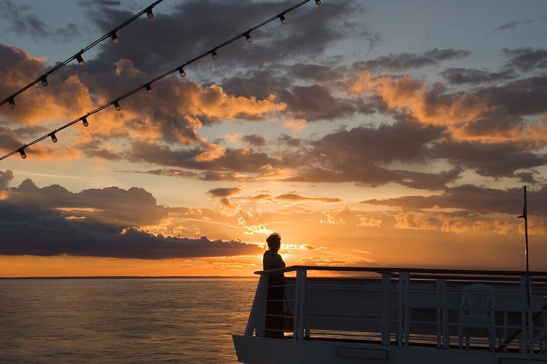 Eine Frau beobachtet den Sonnenuntergang am Meer