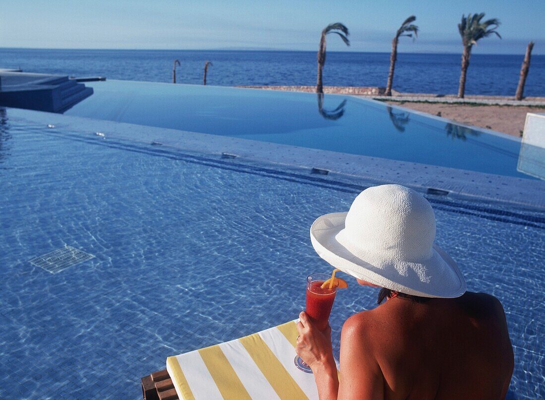 Young Woman Drinking Cocktail At Swimming Pool Deck At Oberoi Sahl Hasheesh Resort