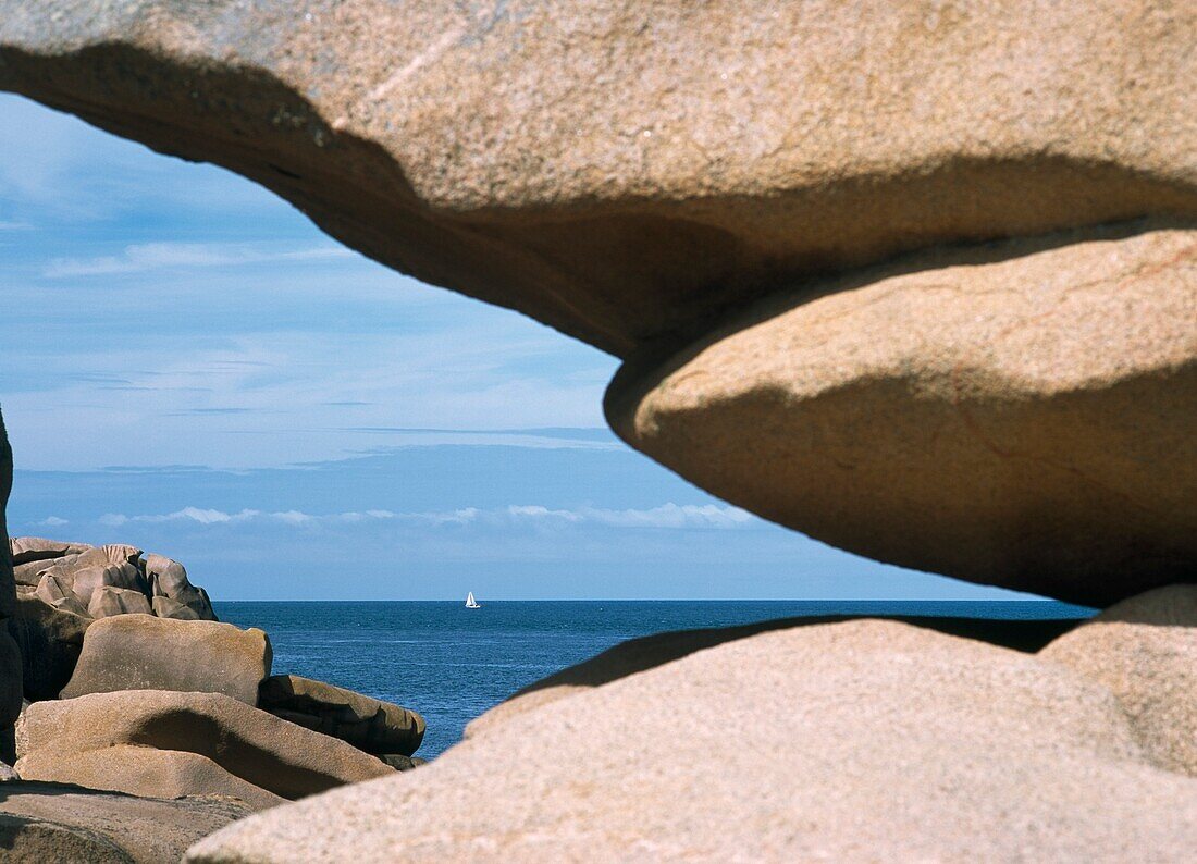 Blick durch eine Felsformation mit einer Yacht in der Ferne