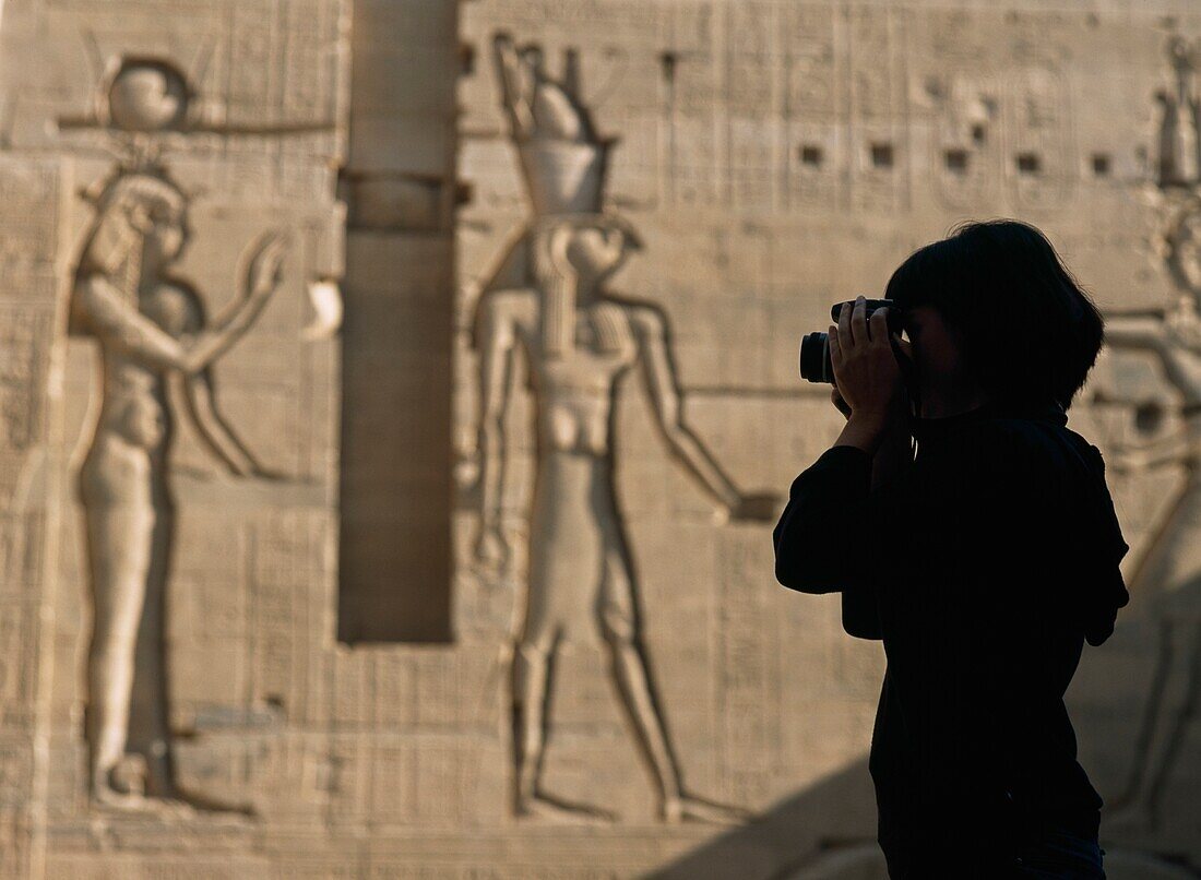 Silhouette eines Touristen, der im Innenhof vor Reliefs Fotos macht