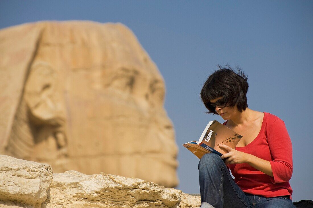 Frau liest Reiseführer vor der Sphinx