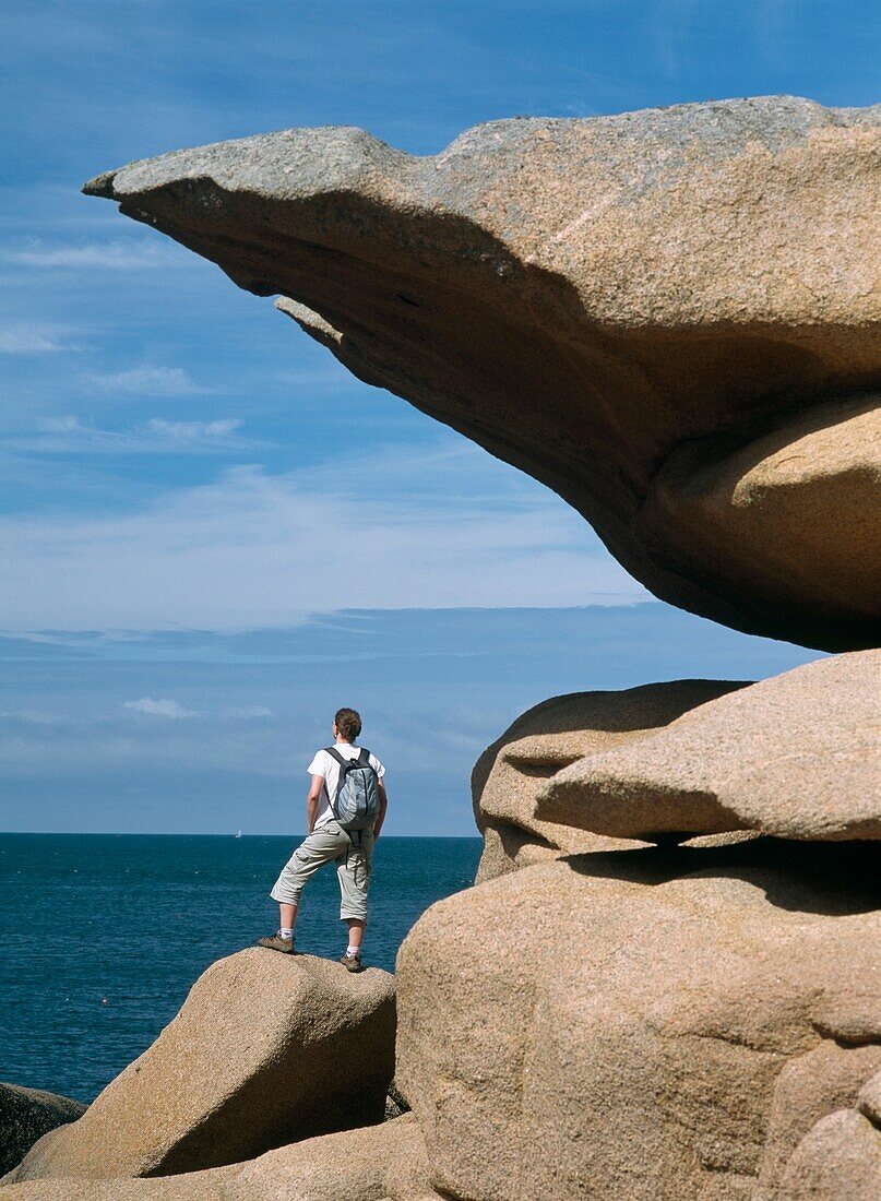 Woman Walker Standing Beside Rock Formation By Sea