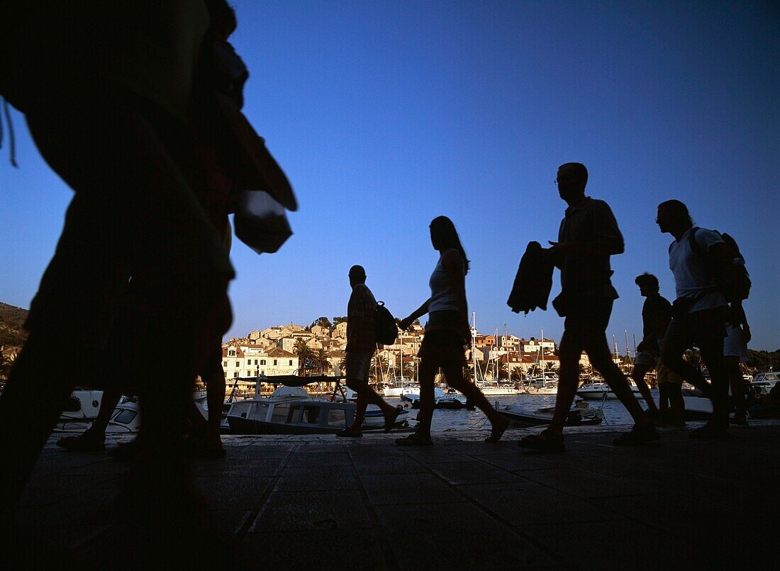 Spaziergänger an der Hafenfront von Hvar in der Abenddämmerung