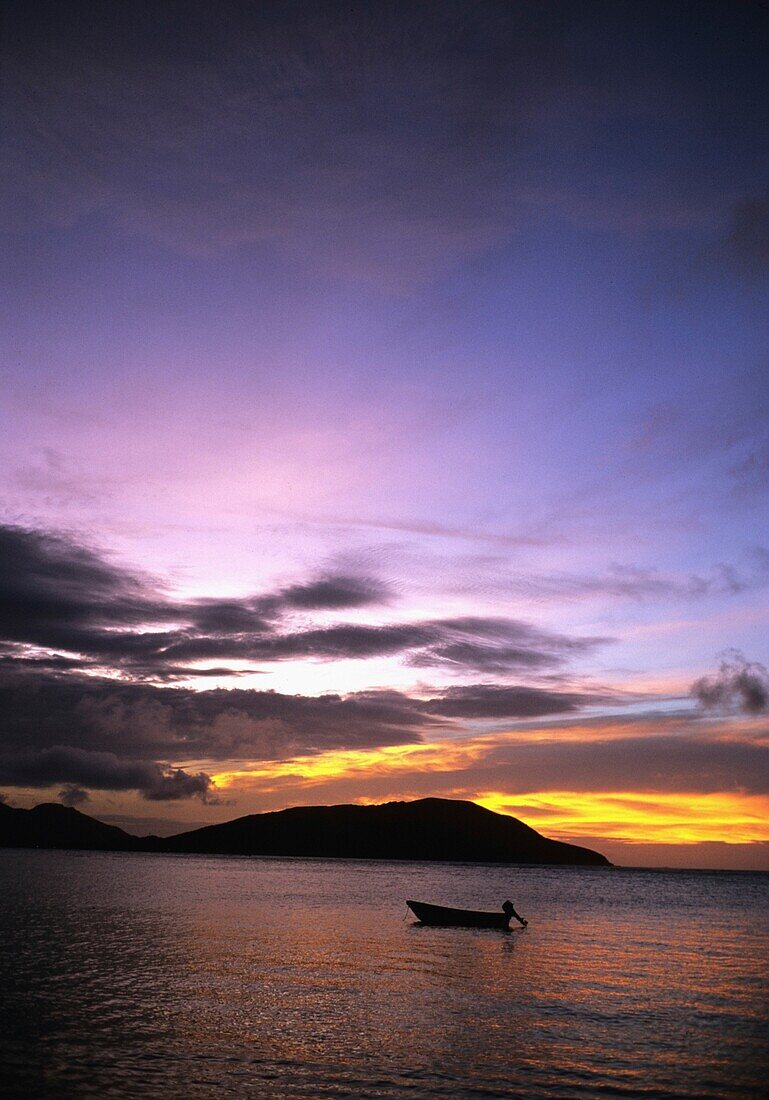 Silhouetted Boat On Sea At Sunset