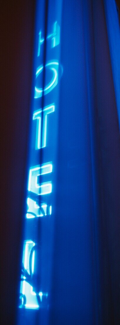 Blaues Neonschild für Hotel durch Netzvorhänge gesehen