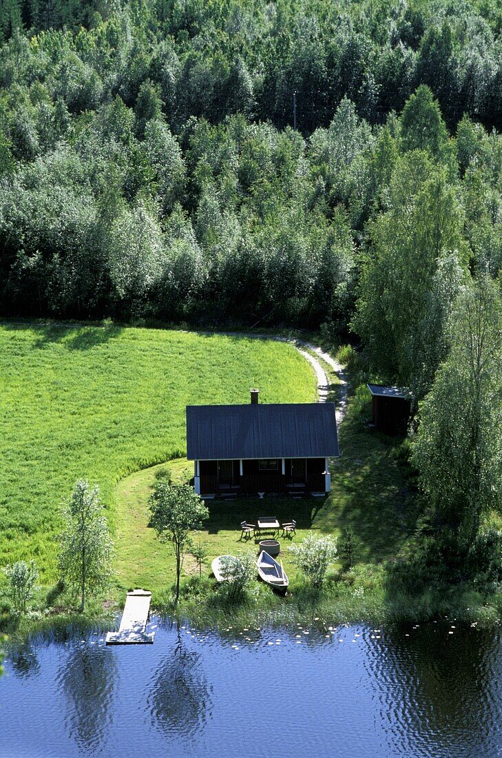 Ansicht einer Hütte neben Wald und See, Luftaufnahme