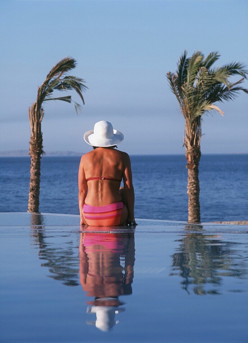 Frau am Pool sitzend, Rückansicht