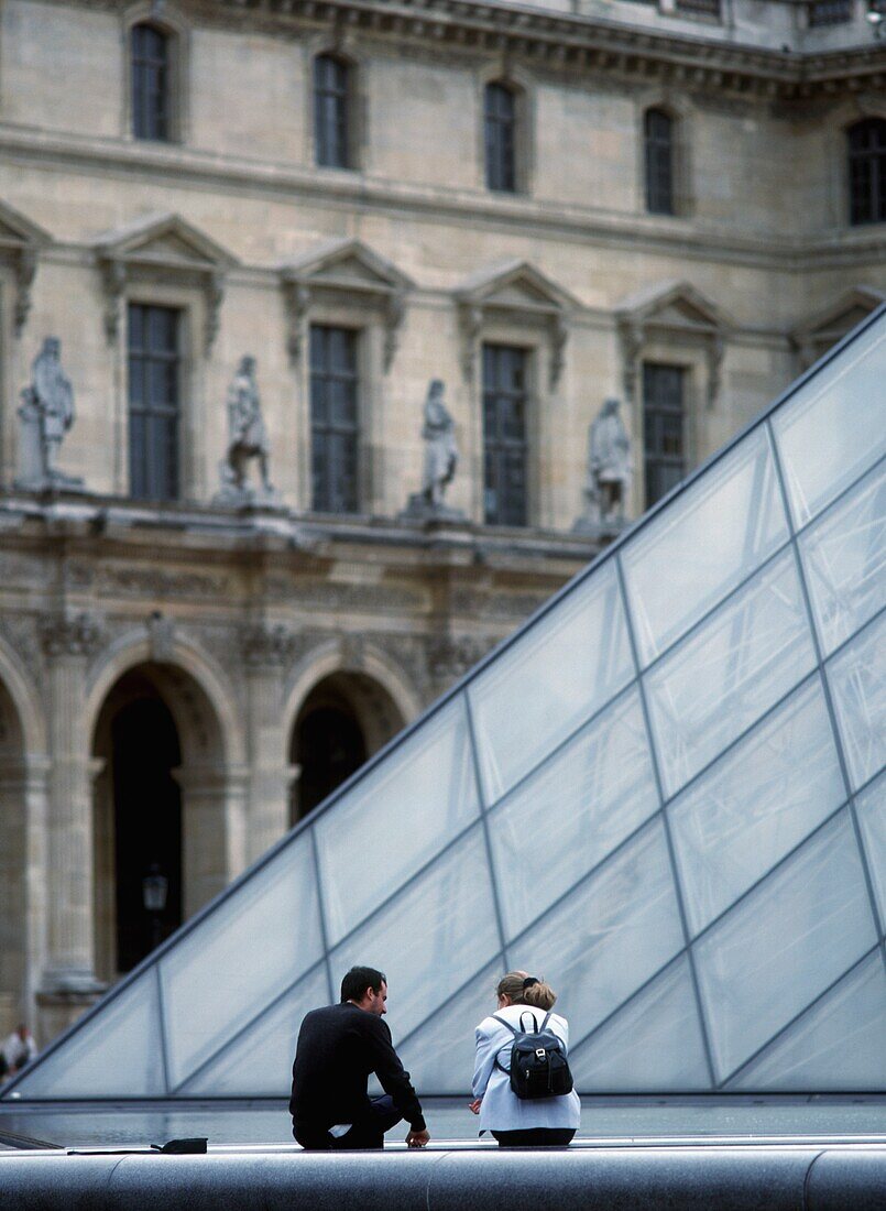 Junges Paar neben der Pyramide im Innenhof des Louvre