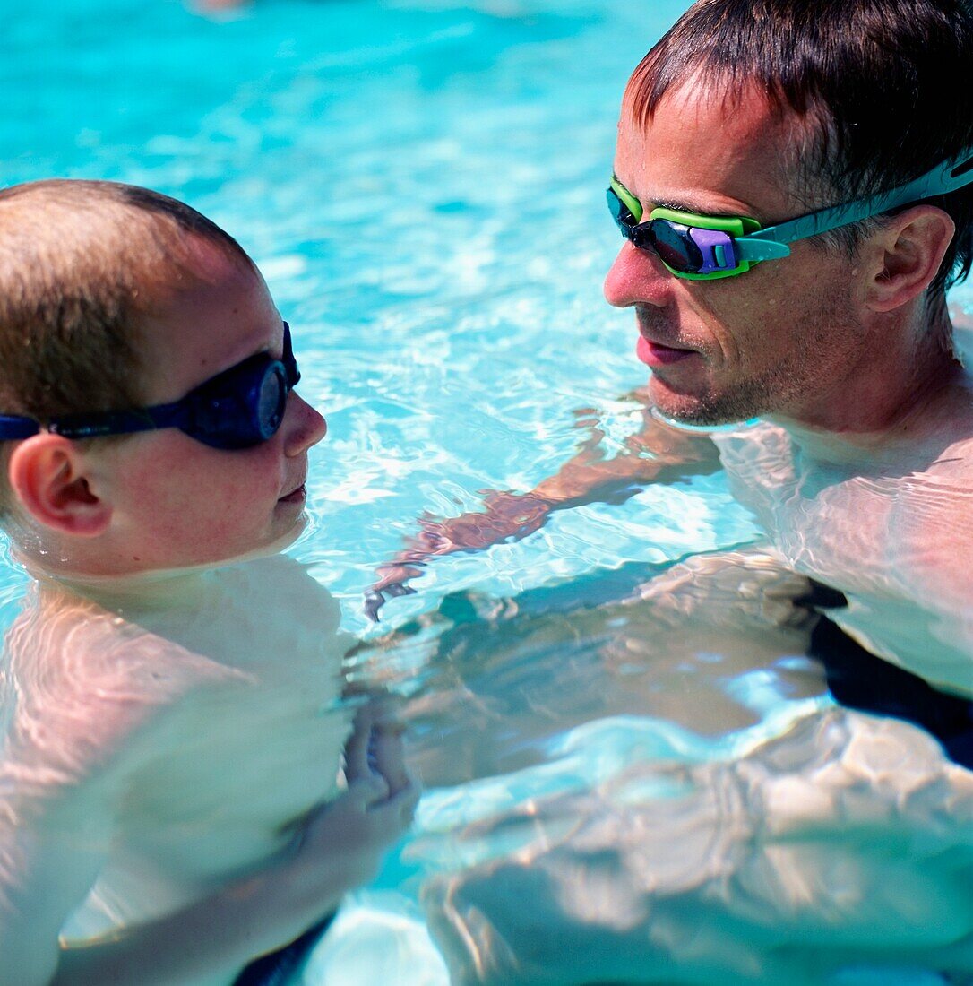 Vater und Sohn mit Schwimmbrille im Pool