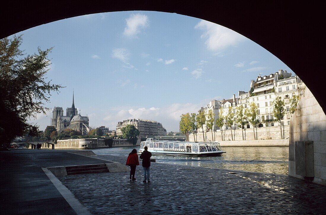 People Walking Under Bridge Near Notre Dame And River Seine