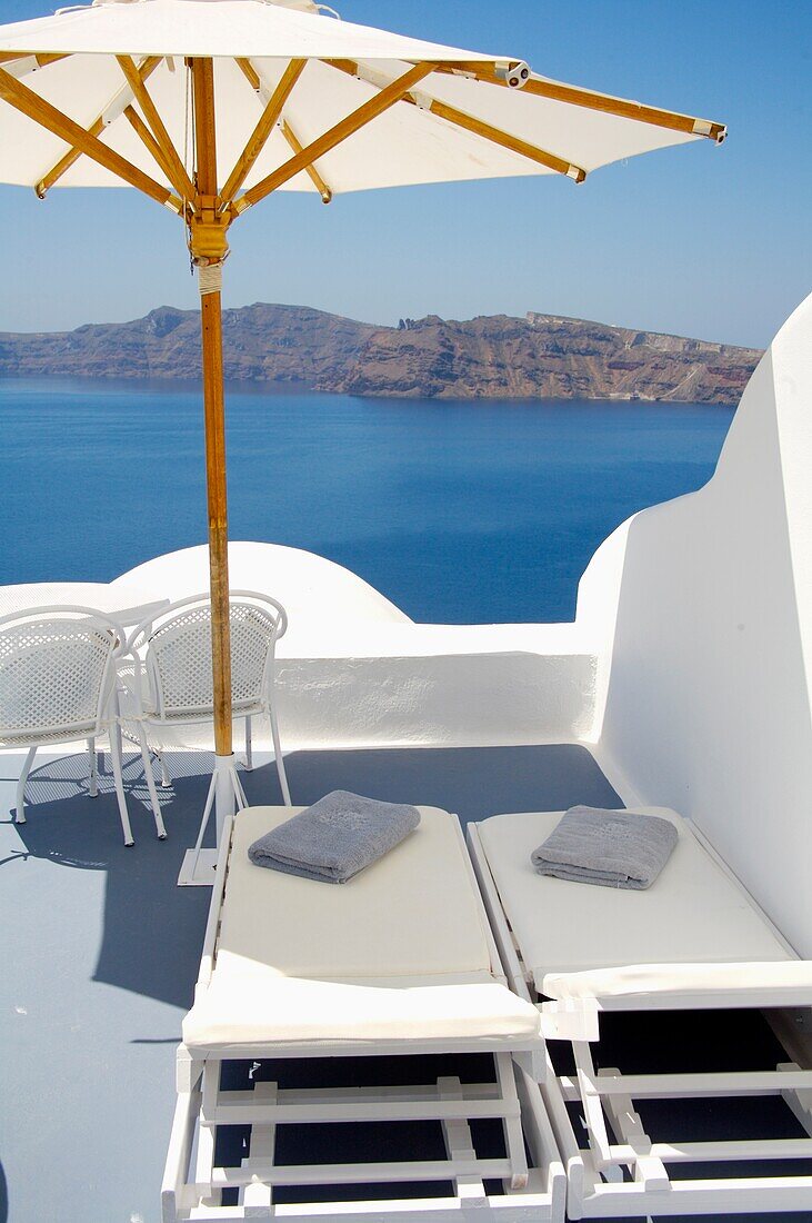 Leere Liegestühle und Sonnenschirm auf der Dachterrasse am Meer