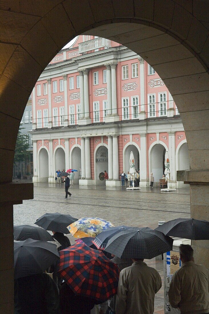 Menschen, die sich vor dem Regen auf dem Neuen Markt schützen