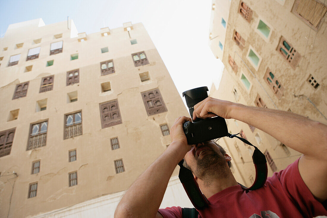 Man Photographing Mud Skyscrapers