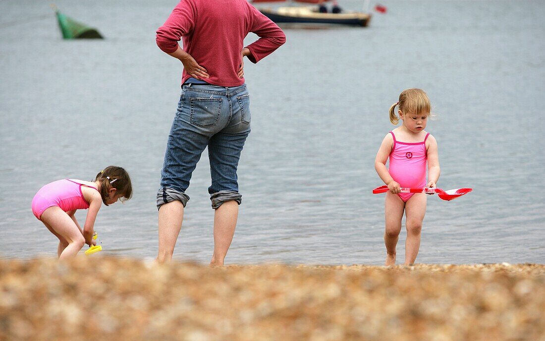 Zwei junge Mädchen spielen mit ihrer Mutter am Strand