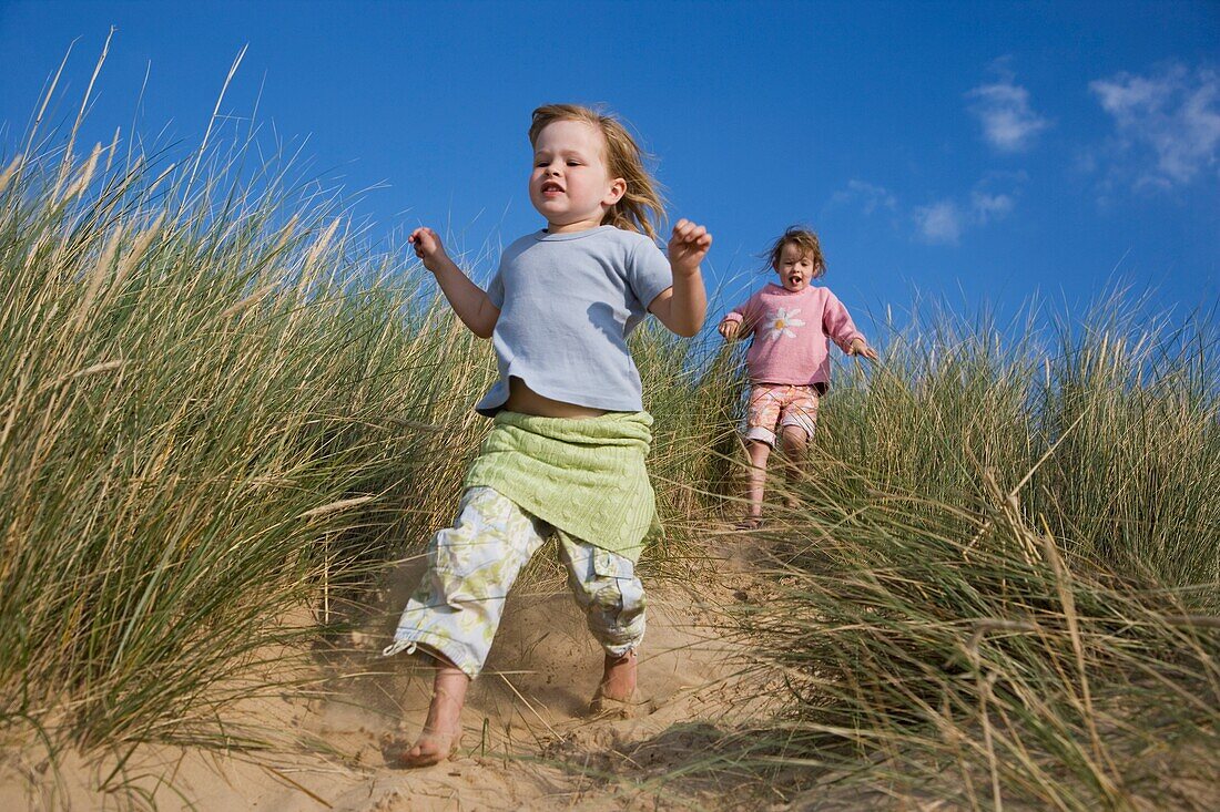 Mädchen rennen die Sanddünen hinunter