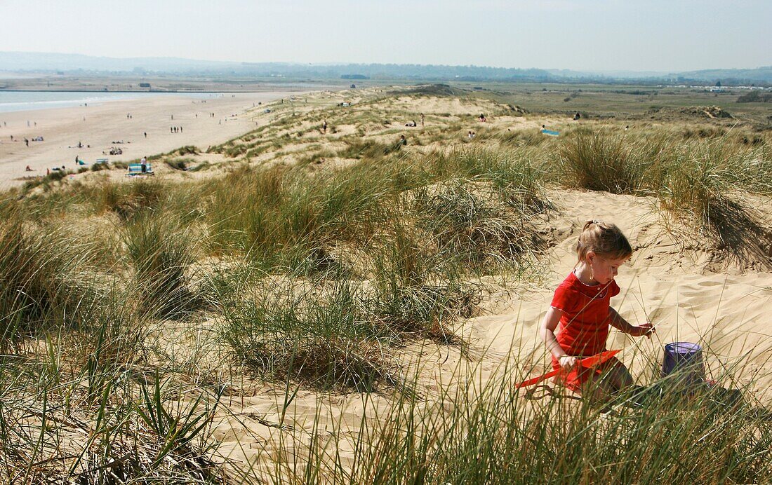 Young Girl Playing On Sand Dune With Bucket And Spade