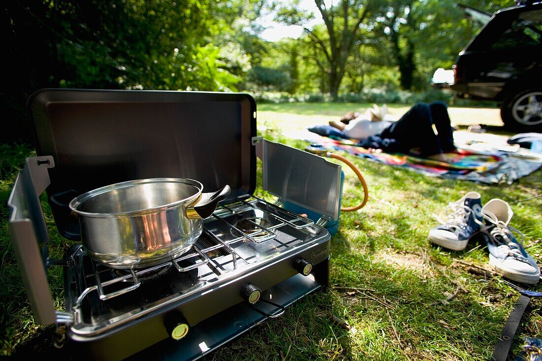 Frau liegend auf dem Campingplatz mit Ofen im Vordergrund