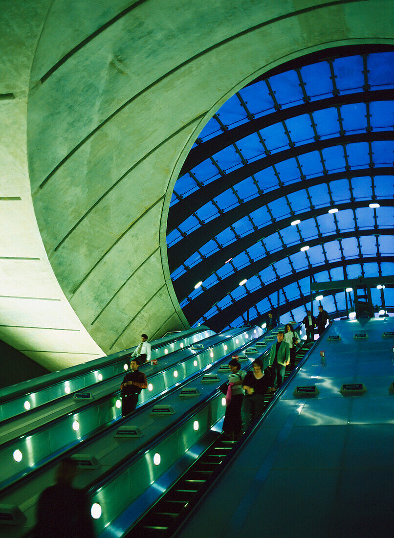 People Going Up And Down Escalators At The Entrance / Exit To Canary Wharf Station (Architect: Sir Norman Foster), London, Uk.