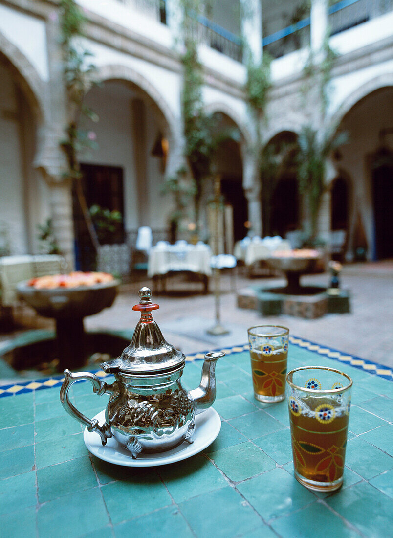 Minztee und zwei Gläser in einem traditionellen marokkanischen Innenhof