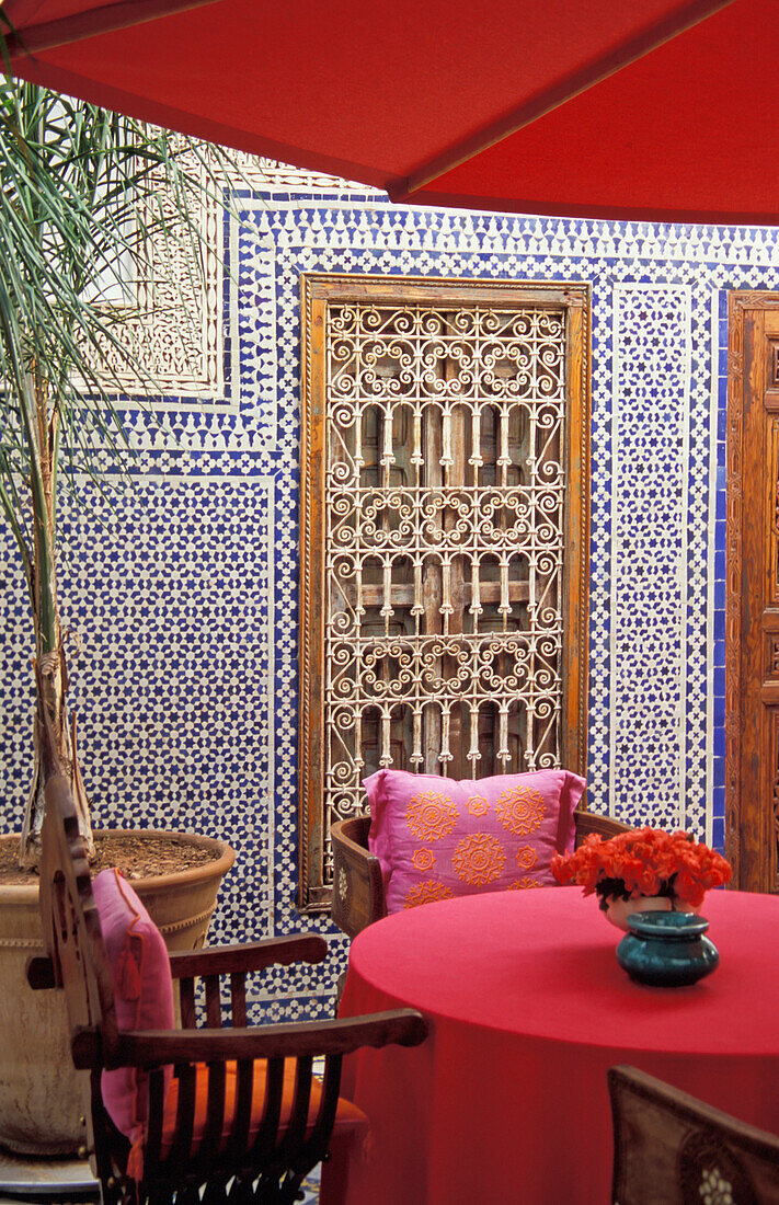 Rosa Tisch mit Schirm im marokkanischen Innenhof