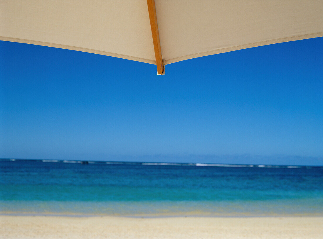 Looking Towards Ocean Through White Beach Umbrella
