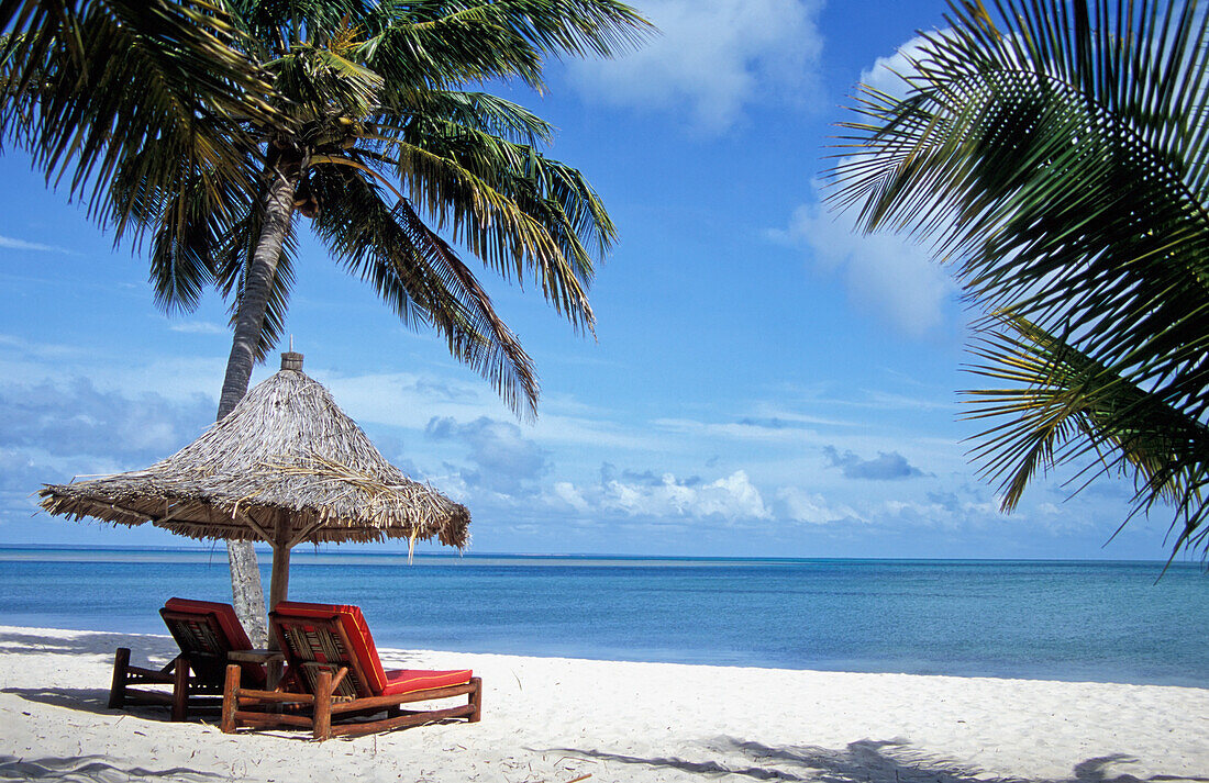 Sun Loungers And Grass Umbrella On Empty Beach