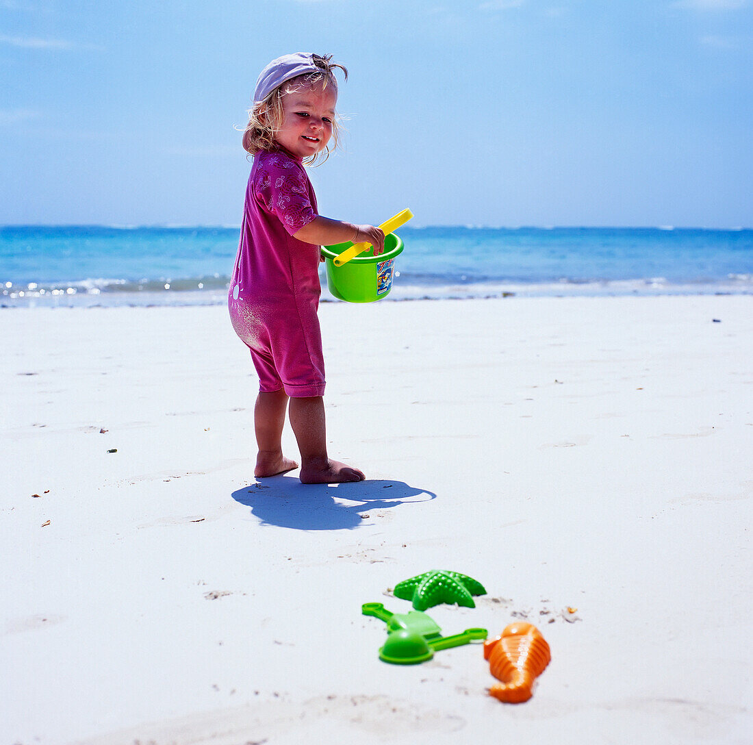 Kind spielt am Strand mit Eimer und Spaten