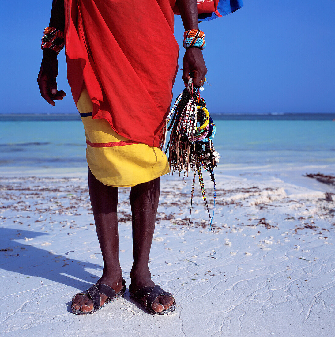Maasai-Verkäufer mit Schmuck am Strand, tiefer Blickwinkel
