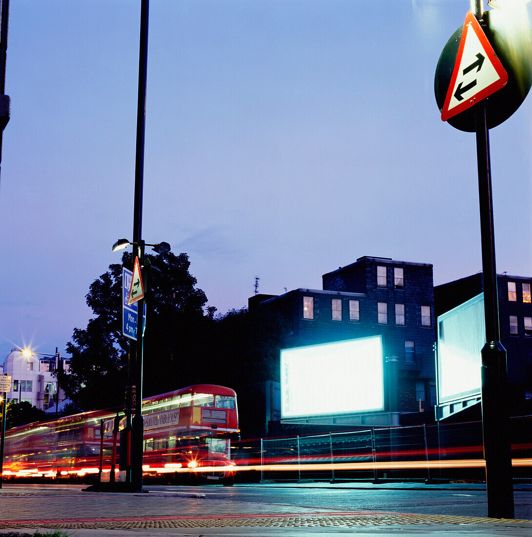 Red Double-Decker Buses On Street In Front Of Billboard, Blurred Motion