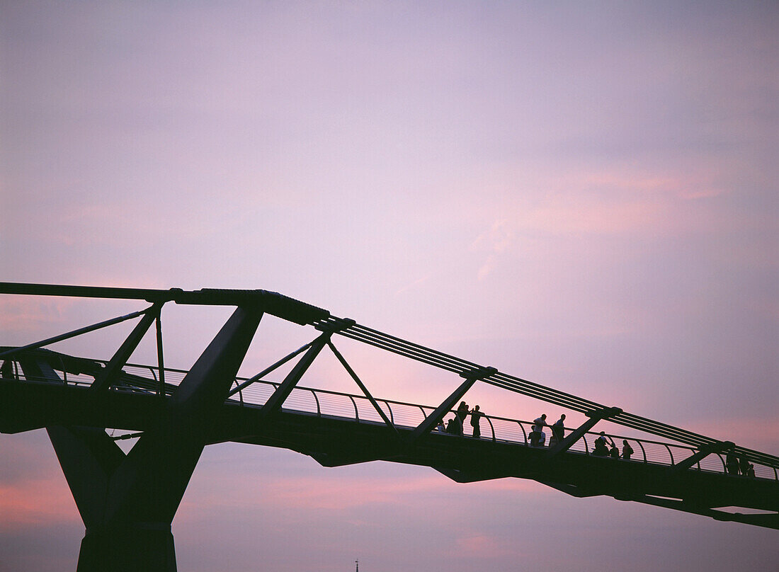 Silhouette von Menschen, die in der Abenddämmerung die Millennium Bridge überqueren