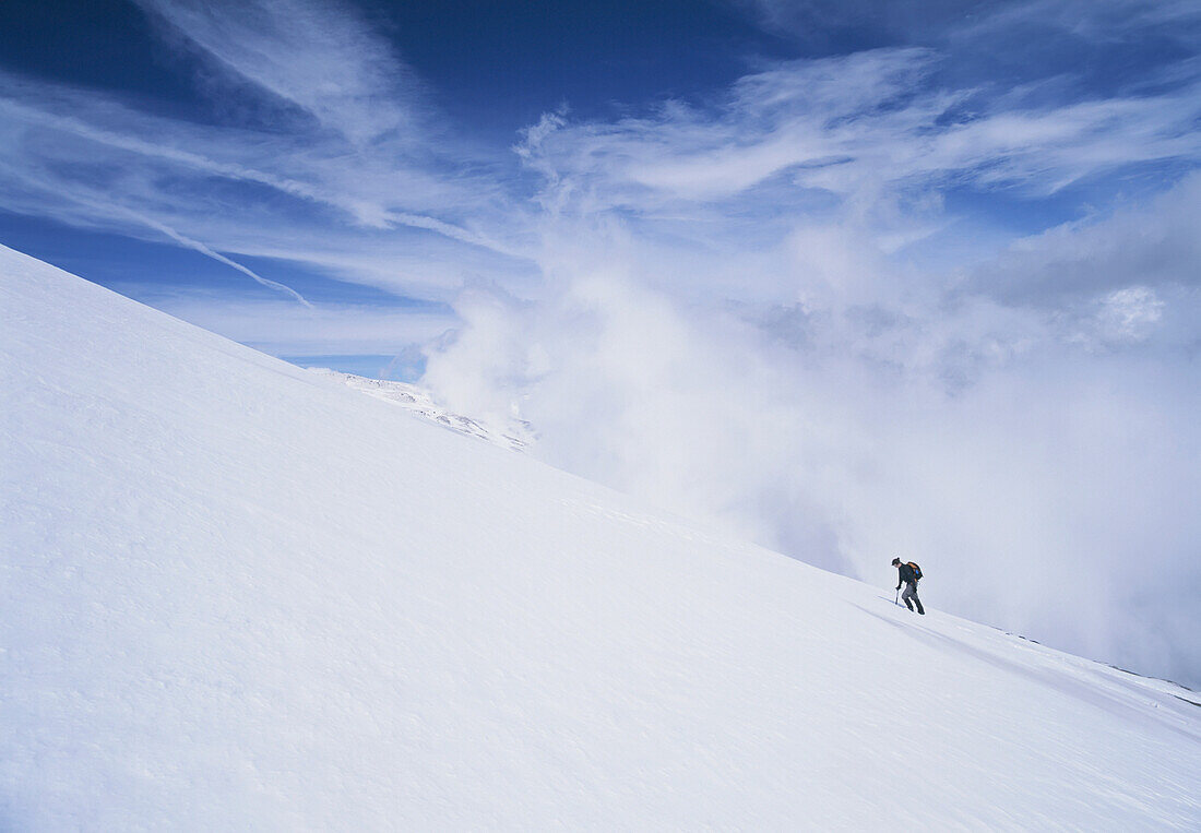 Frau geht einen verschneiten Hang in der Sierra Nevada hinauf