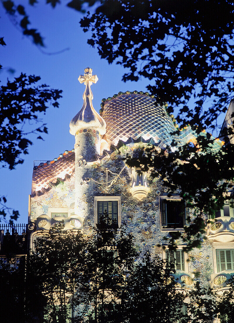 Außenansicht der Casa Batllo in der Abenddämmerung mit Bäumen