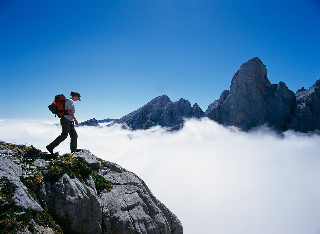 Hiker On Mountain Peak Surrounded By Clouds