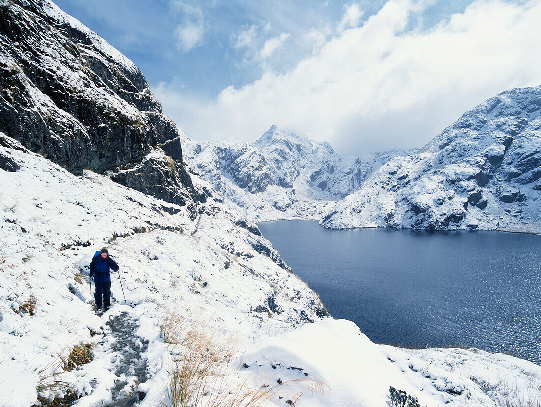 Frau wandert in einer verschneiten, bergigen Landschaft