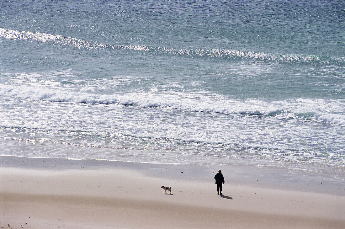 Mann, der mit seinem Hund am Strand spazieren geht, hoher Blickwinkel