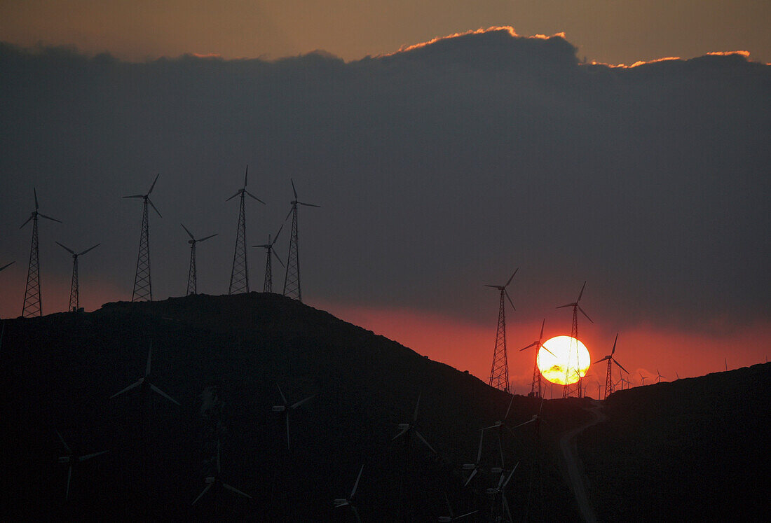 Sonnenuntergang hinter Windturbinen in einem Windpark auf einem Berg bei Tarifa