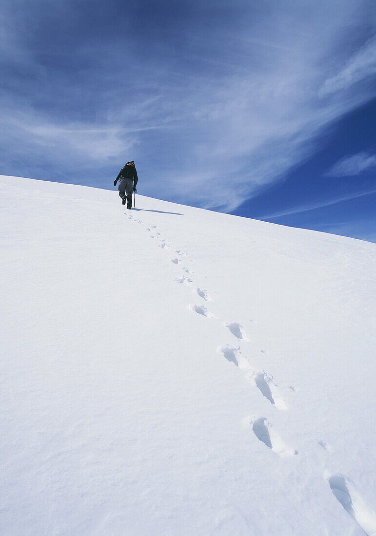 Bergsteiger, der einen verschneiten Abhang in der Sierra Nevada hinaufgeht