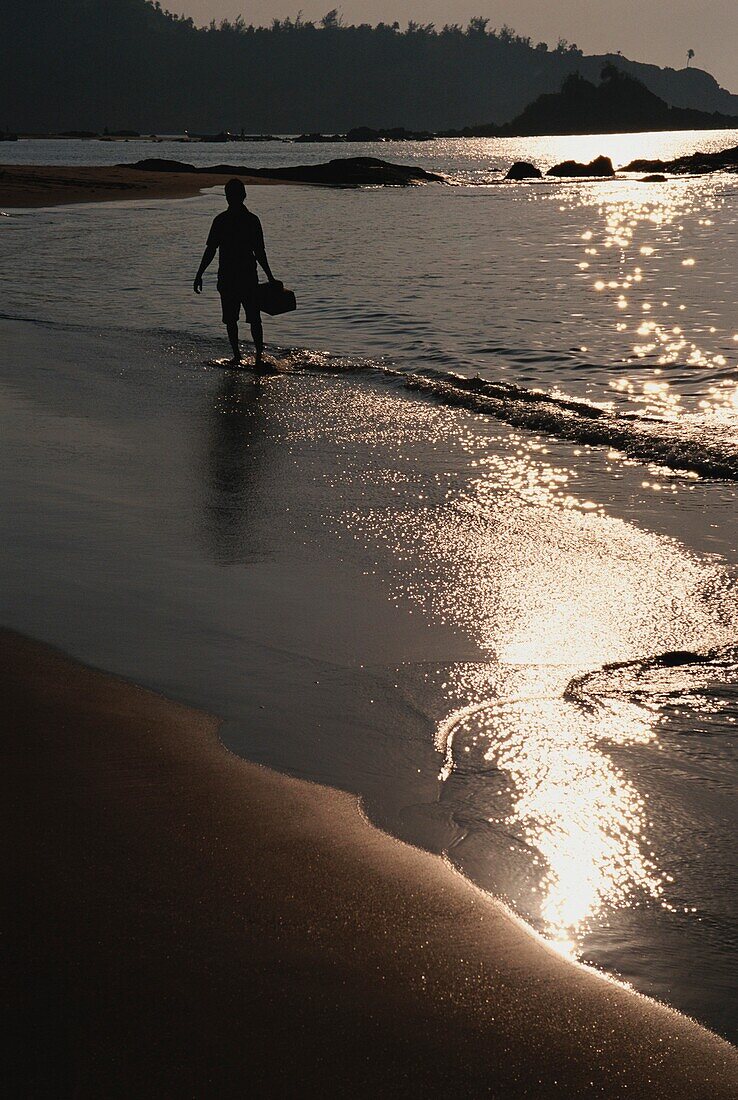 Mann in Silhouette spaziert entlang Om Beach