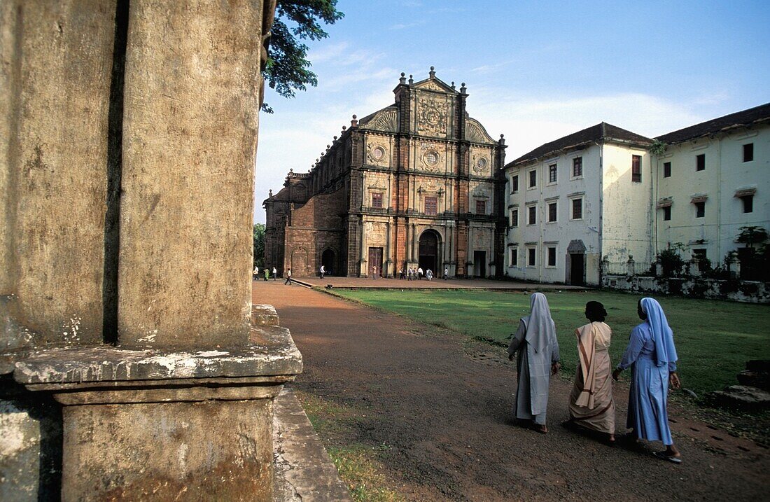 Frau geht neben zwei Nonnen vor einer Kirche in Goa spazieren