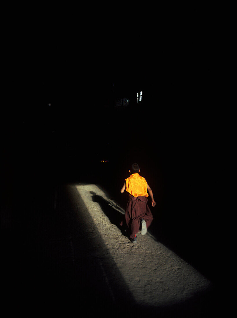 Young Monk Running Into Prayer Hall Of Tsemo Monastery