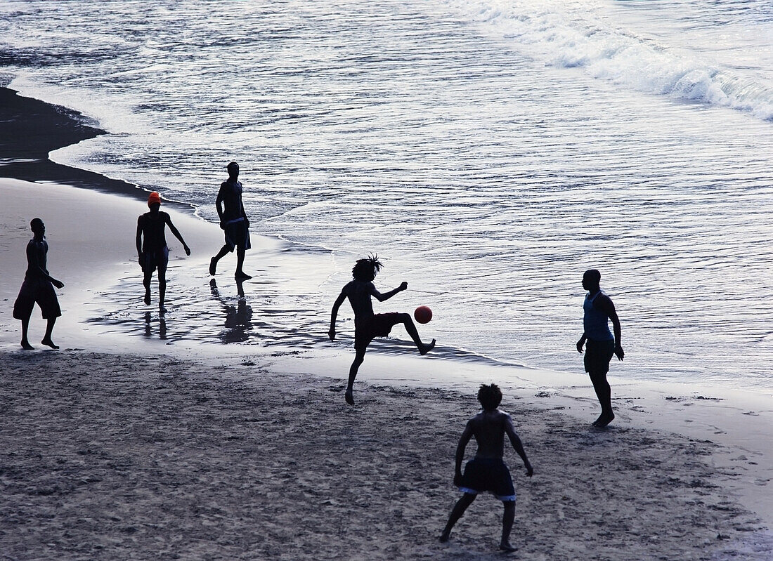 Young Men Playing Football On The Beach