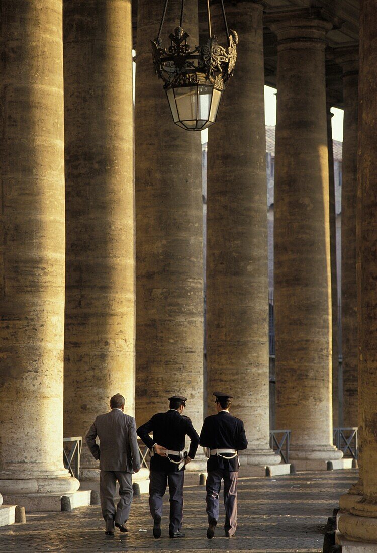 Two Police And Man Walking Beside Colonnade In St Peters Square