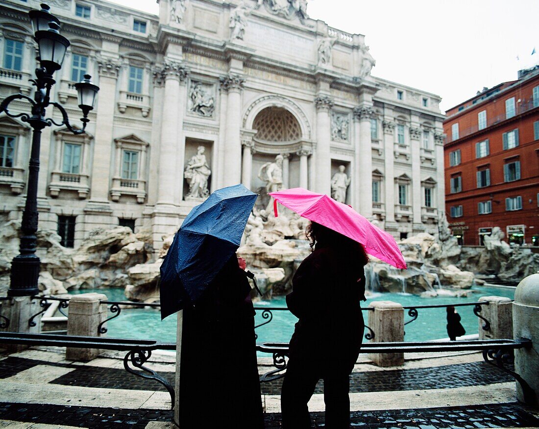 Zwei Touristen am Trevi-Brunnen mit Regenschirmen