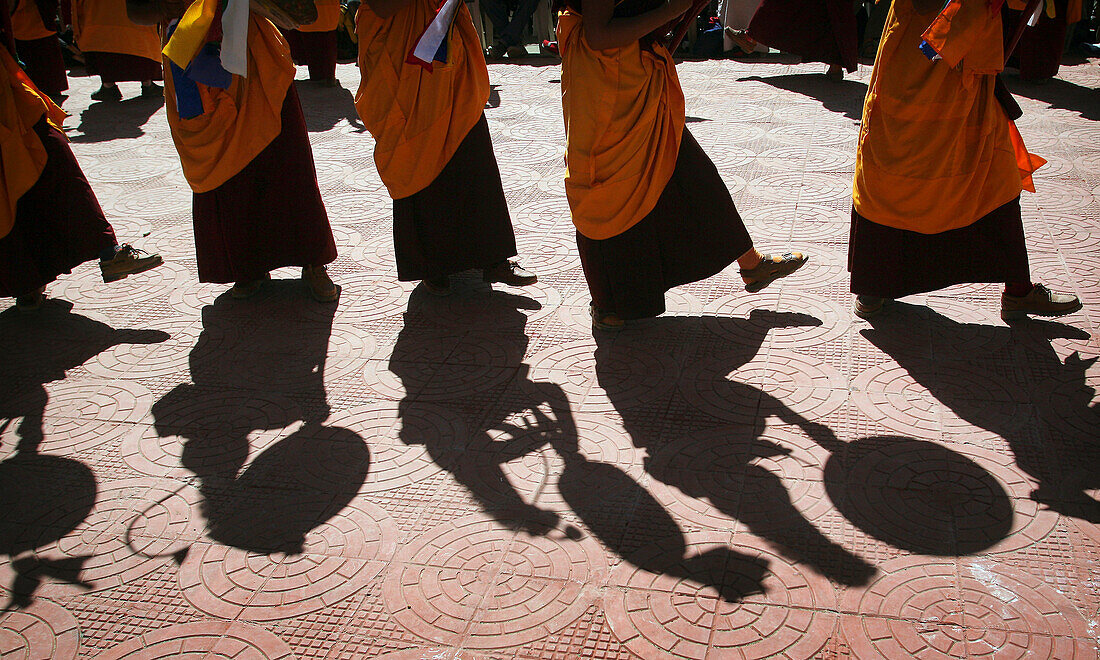 Monks In Traditional Dress With Yellow Orange Hats And Robes Dancing And Banging Drums, Low Angle View
