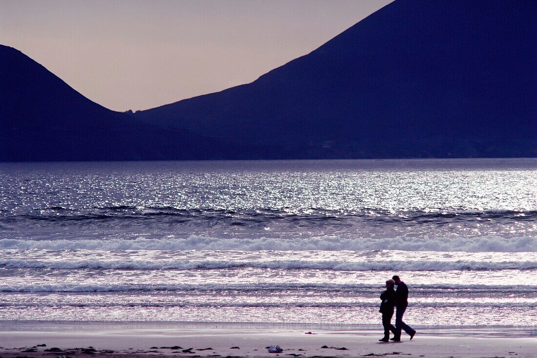 People Walking Along Beach In Silhouette